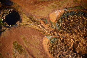 Water flows over a stone, there is some ocher settlement.