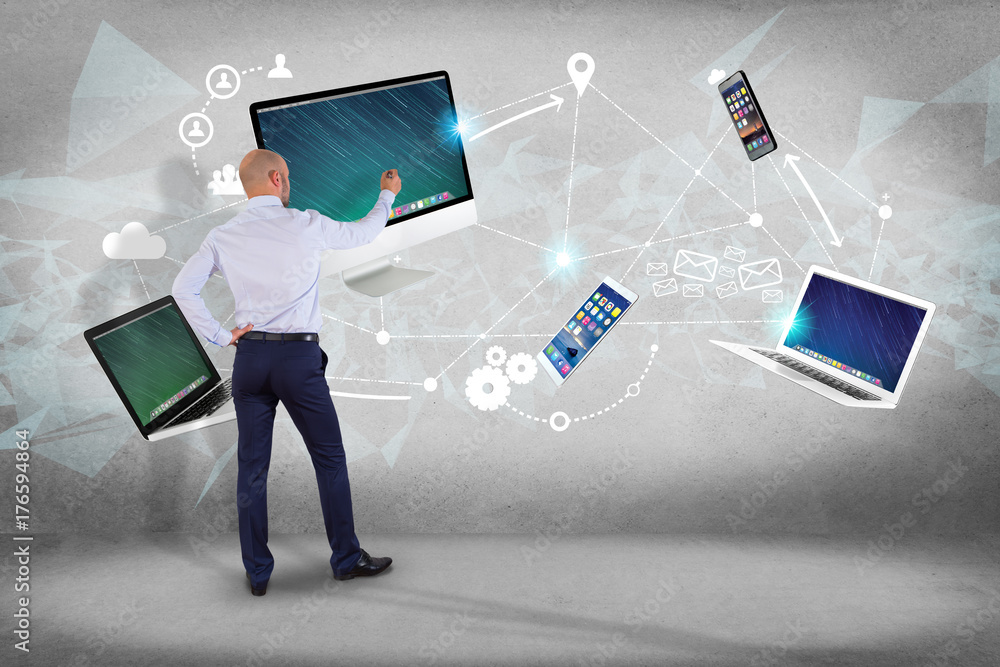 Poster businessman in front of a wall with computer and devices displayed on a futuristic interface with in