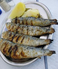 Grilled sardines with boiled potatoes closeup