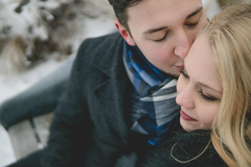 Glückliches Paar in Winterlandschaft sitzt auf Parkbank