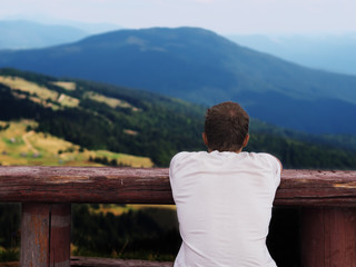 Man looking at the mountains view from back sitting