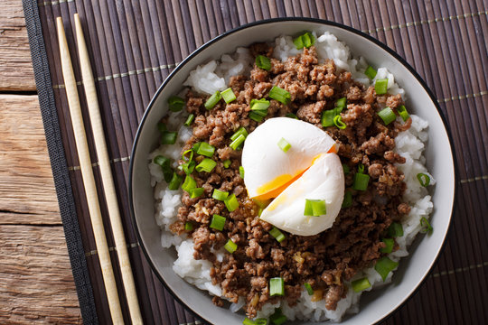 Japanese dish: spicy meat Soboro with egg poached and rice close-up in a bowl. horizontal top view