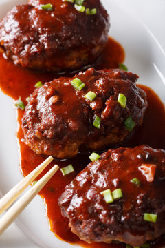 Japanese food: hamburg steak or hambagu with a spicy sauce on a plate macro. vertical