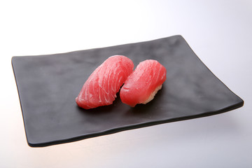 Two fresh tuna sushi on a black dish
