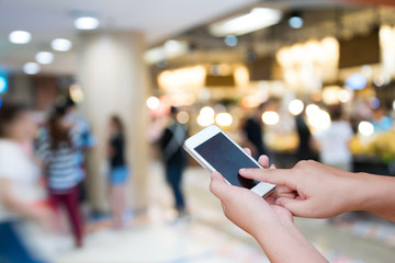 blurred photo and smartphone on shopping mall and people with bokeh.