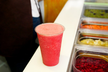 Fruit smoothie ready for sales in plastic cup with straw. Take away drinks concept. Fresh fruits juices at the public market. Various fresh fruit and vegetable salad bar healthy items. Healthy drink.
