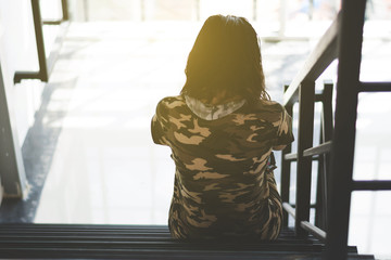 depress and hopeless woman sitting on ladder in house with arm around knee and lower head, abuse...