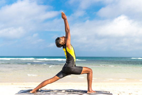 Asian yoga man practice yoga on the beach with a clear blue sky background. Yogi on the tropical beach of Bali island, Indonesia.
