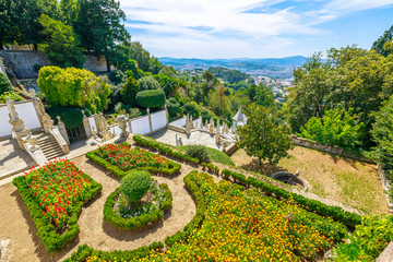 Spectacular aerial view of flowering garden in front of Sanctuary of Bom Jesus do Monte and the monumental baroque staircase. Cityscape of Braga from top of mountain. Tenoes, Braga, north of Portugal.