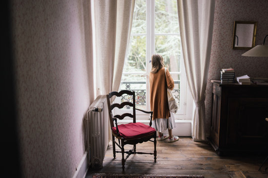 Petite fille de dos qui regarde par la fen&ecirc;tre