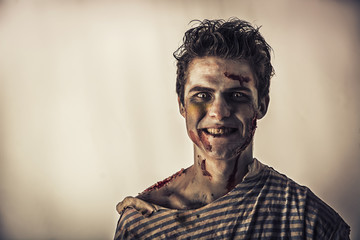 Fototapeta premium Male zombie standing on dark background, smiling to the camera