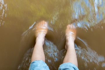 The boy's feet are soaked in the river