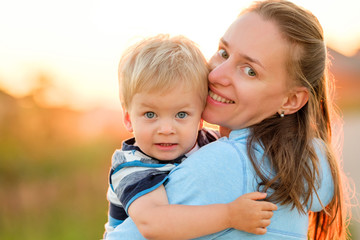 Woman and child having fun outdoors in sunset sunlight