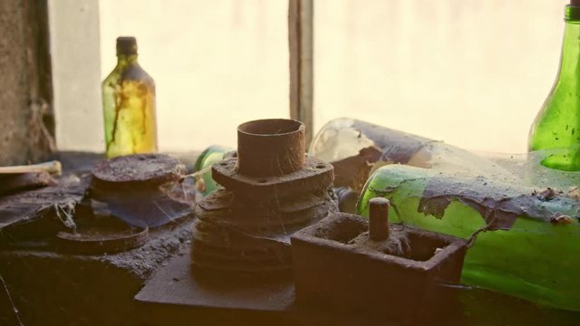 abandoned place workshop. Detail view from a dusty window. On the window sill are oil cans, bottles, Hingelegtes, material. Cobwebs tell of yesteryear. The workshop is very old.