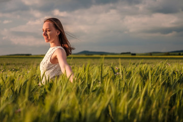 Beautiful woman in white dress on green wheat field