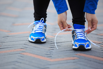 Plakat Young woman runner tying shoelace before run