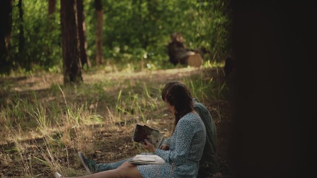 Couple sitting in picnic in the sunset forest. Family looking at their photo album sitting in the park. Happy couple with photo album.A young attractive couple walking through the forest with their