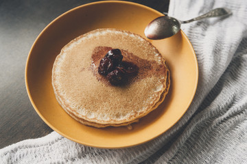 Homemade pancakes on the yellow plate with cherry jam