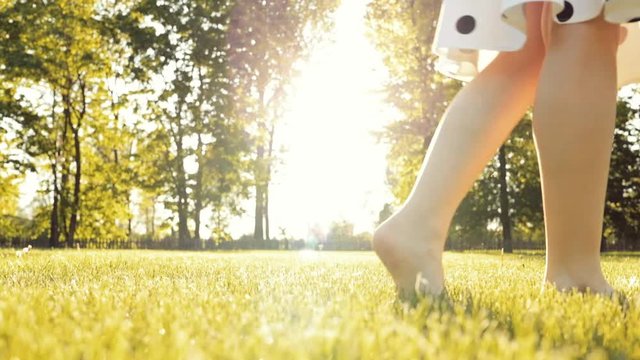 Barefoot Woman Feet Walking in the Green Grass in the City Park. 4K DCi SLOW MOTION. Female legs stepping on a lawn outdoors, close up. Lens Flare