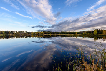 autumn colored trees on the shore of lake with reflections in water