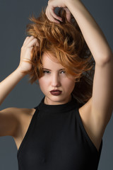 red-haired girl in a black dress on a gray background
