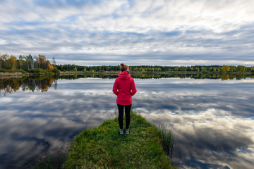 young woman in red jacket enjoying nature on dirt road. Latvia