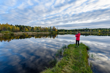 Fototapeta na wymiar young woman in red jacket enjoying nature on dirt road. Latvia