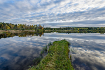autumn colored trees on the shore of lake with reflections in water
