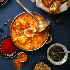 Indian cuisine on diwali holiday: tikka masala, samosa, patties and sweets with mint chutney and spices. Dark blue background. Square composition