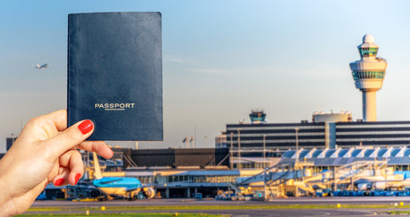 Naklejka premium Digital composite of hand holding a generic passport with busy airport terminal in blurred background