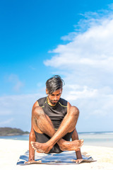 Fototapeta na wymiar Asian yoga man practice yoga on the beach with a clear blue sky background. Yogi on the tropical beach of Bali island, Indonesia.