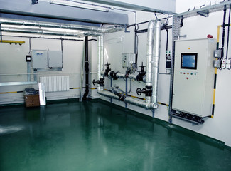 The interior of a modern industrial gas boiler room. Pipelines, water pumps, valves, manometers.