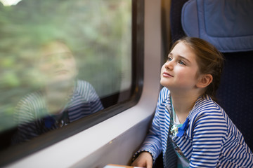 Cute girl looking through window in moving train