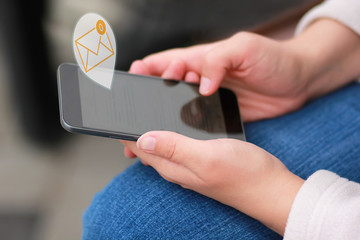 Close up of woman's hands scrolling the black smart phone and reading all the e-mails to reach inbox zero, against blurred background
