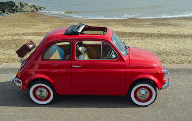  Classic Red Fiat 500  motor car with picnic basket parked on seafront promenade. - obrazy, fototapety, plakaty