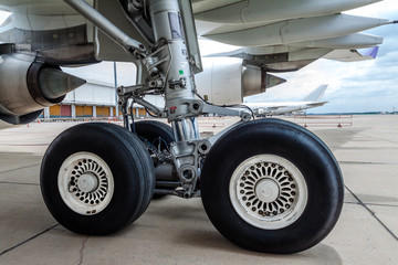 close up of airplane wheel parked at the airport - obrazy, fototapety, plakaty