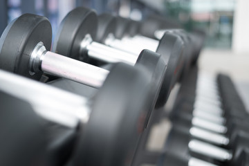 Obraz na płótnie Canvas Row of dumbbells in gym. Black dumbbell set in sport fitness center.