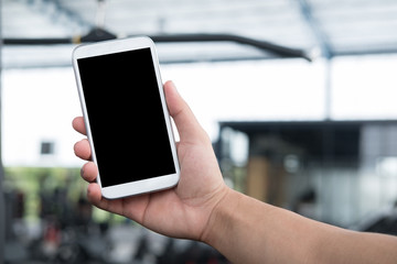 male's hand hold mobile phone in gym. man with smartphone in fitness center. cellphone in health club.