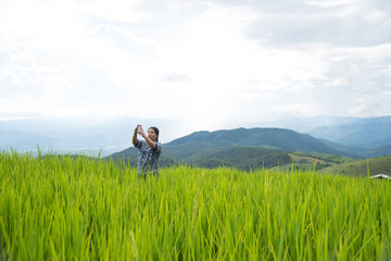Fototapeta na wymiar A woman, tourism standing and take photo beautiful view green rice fields on terraces in Thailand at Ban Pa Pong Pieng in Mae chaem, Chaing Mai. 