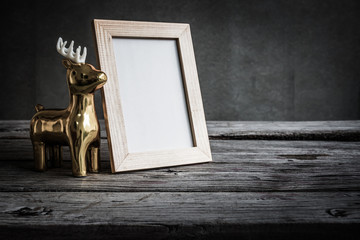 Holidays concept, Christmas and Happy New Year festive background, vintage photo frame with golden deer on wooden table