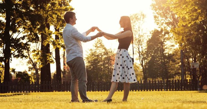 Young Couple Meeting in the City Park, Hugging and Kissing. 4K DCi SLOW MOTION. Beautiful romantic man and woman running to each other, embrace and share a kiss on sunset outdoors. 