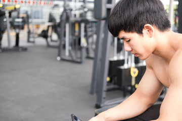 young man use mobile phone in fitness center. male athlete text message in cellphone in gym. sporty guy check social news in smart phone in health club after working out.