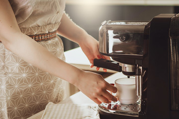 Woman making fresh espresso in coffee maker. coffee machine makes coffee.