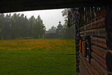A vintage church in the rain. View from the porch/A summer downpour. The forest and the vintage Church in the rain. The Museum of wooden architecture. Kostroma, Russia. Landscape, nature