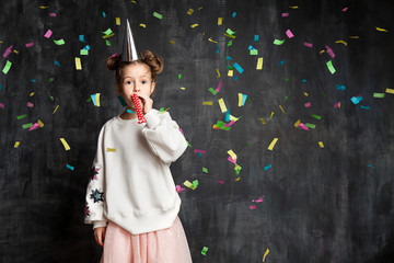 Little fashionable girl having fun at the birthday party on the background of a school board and confetti © deniskomarov