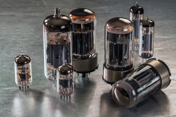 Radio tubes of different sizes lie on a metal surface