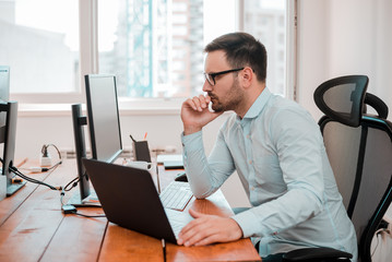 Handsome young man working with computer in modern office.