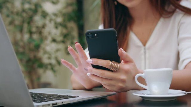 A beautiful girl using her mobile phone and a laptop in the room. Closeup shot. Soft focus.