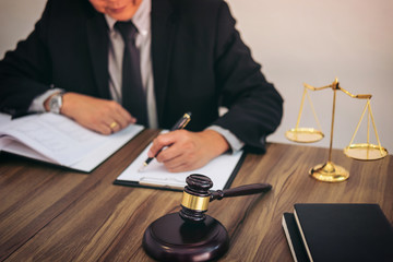 Gavel on wooden table and Lawyer or Judge working with agreement in Courtroom theme, Justice and Law concept