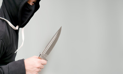 The male criminal in action of attacking with knife. Isolated on gray background. The concept of crime for presentation slide.